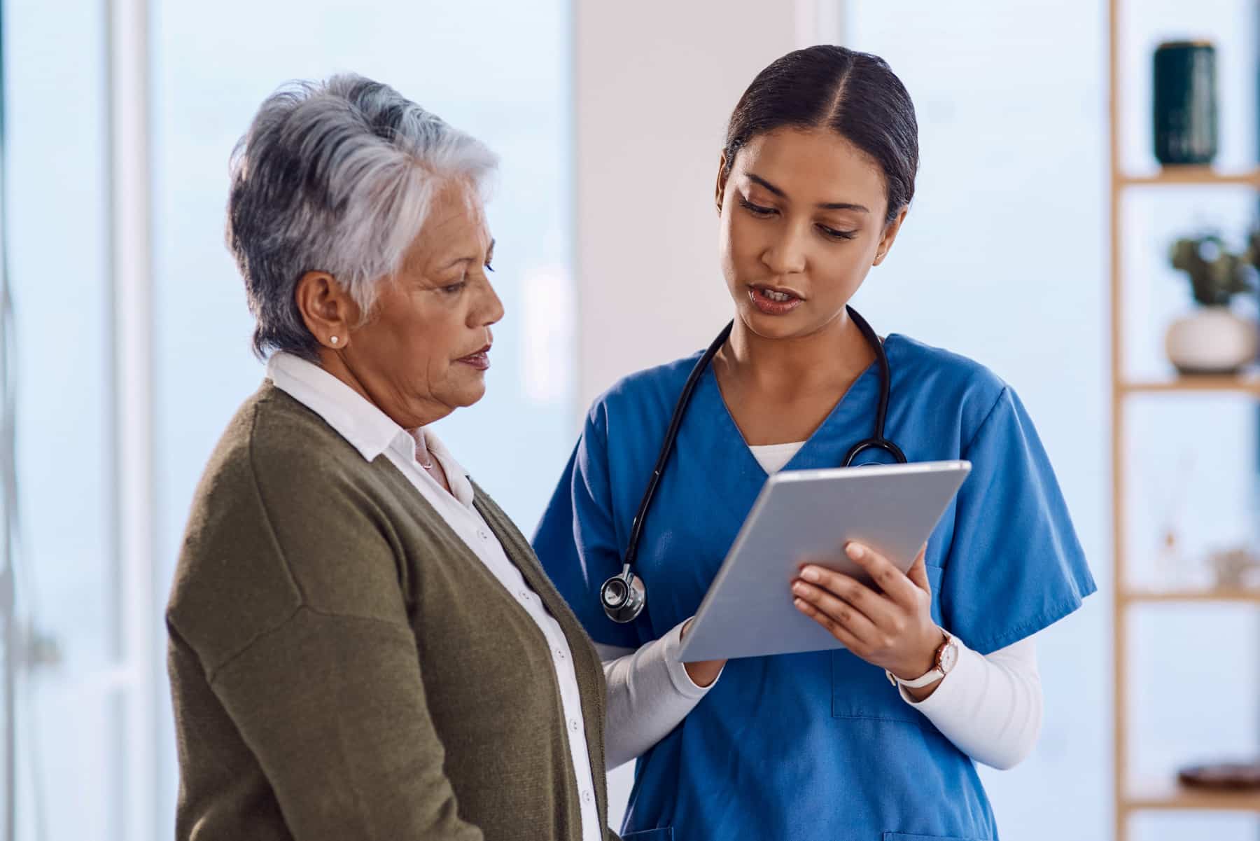 Medical professional reviewing data on tablet with patient