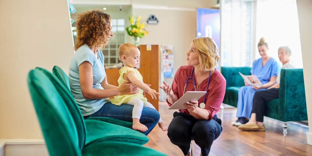 Nurse speaking with mother of newborn baby in waiting room