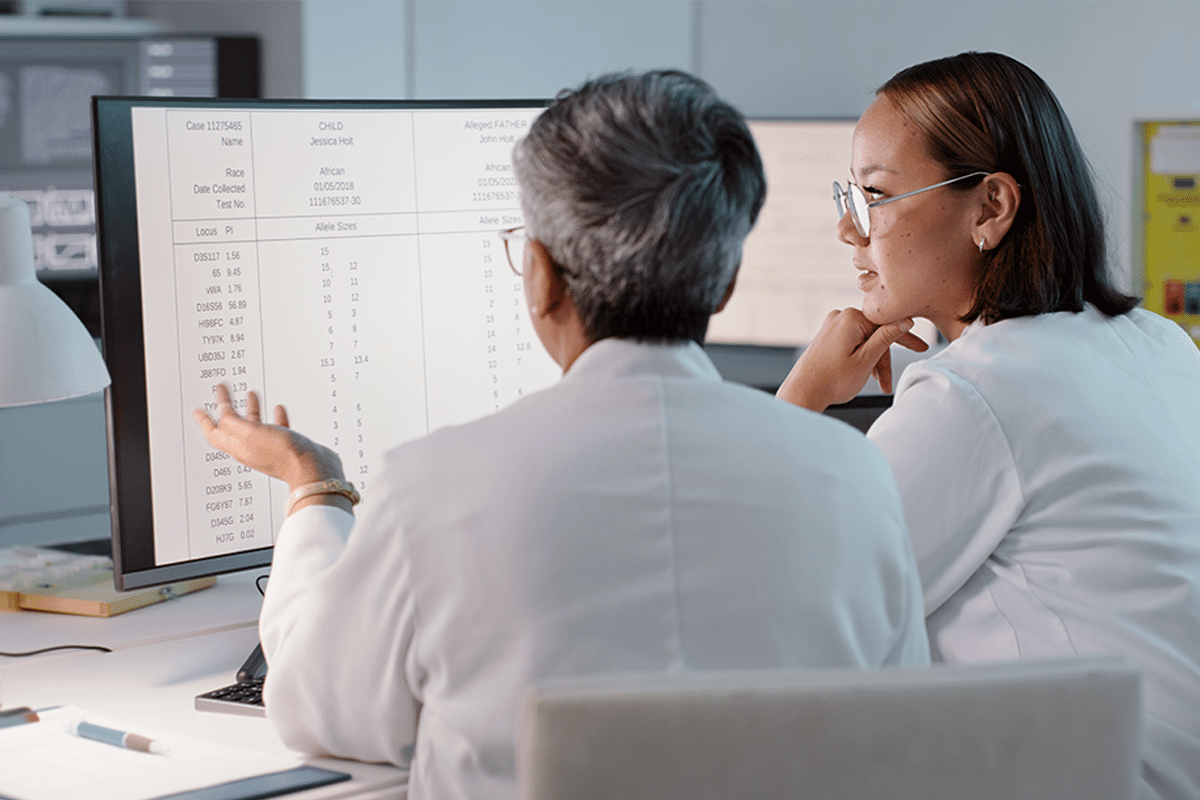 Two physicians looking at a computer with data in spreadsheets