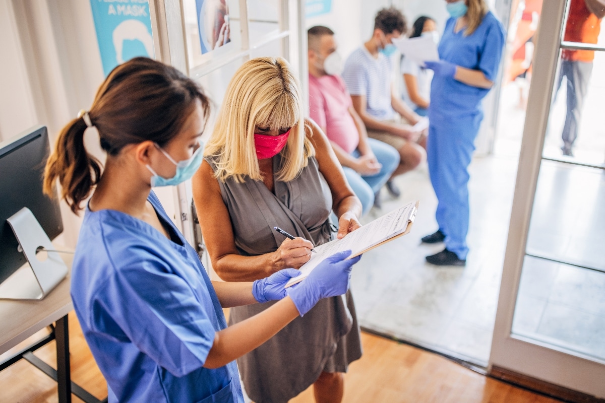 A patient fills out a paper form with a nurse, showing a chance to improve patient experience.