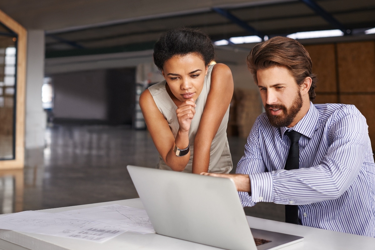 Two professionals review master data management implementation styles on a computer screen.