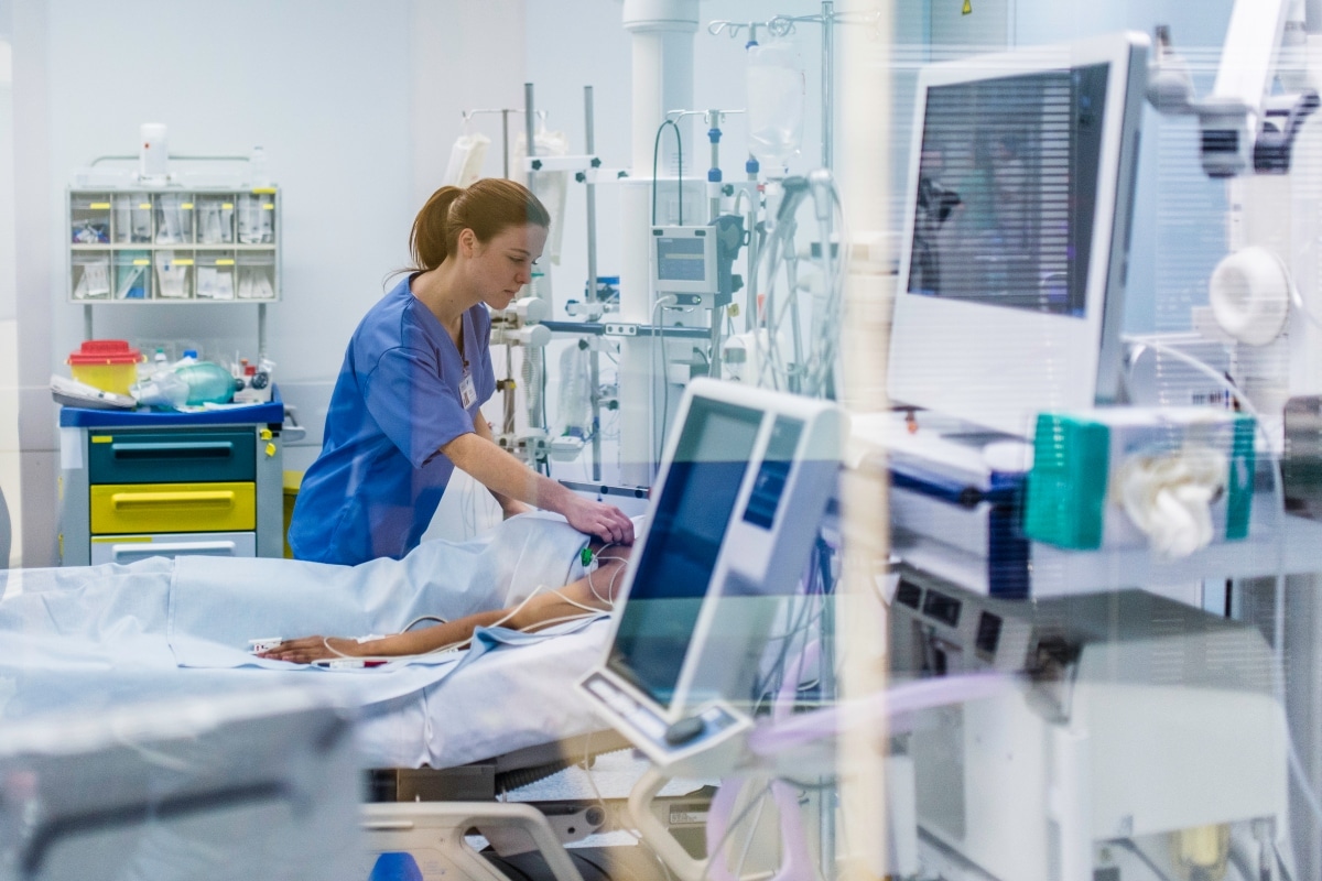 Nurse tends to a patient on an ER stretcher, where a matching error can hide their medication list.