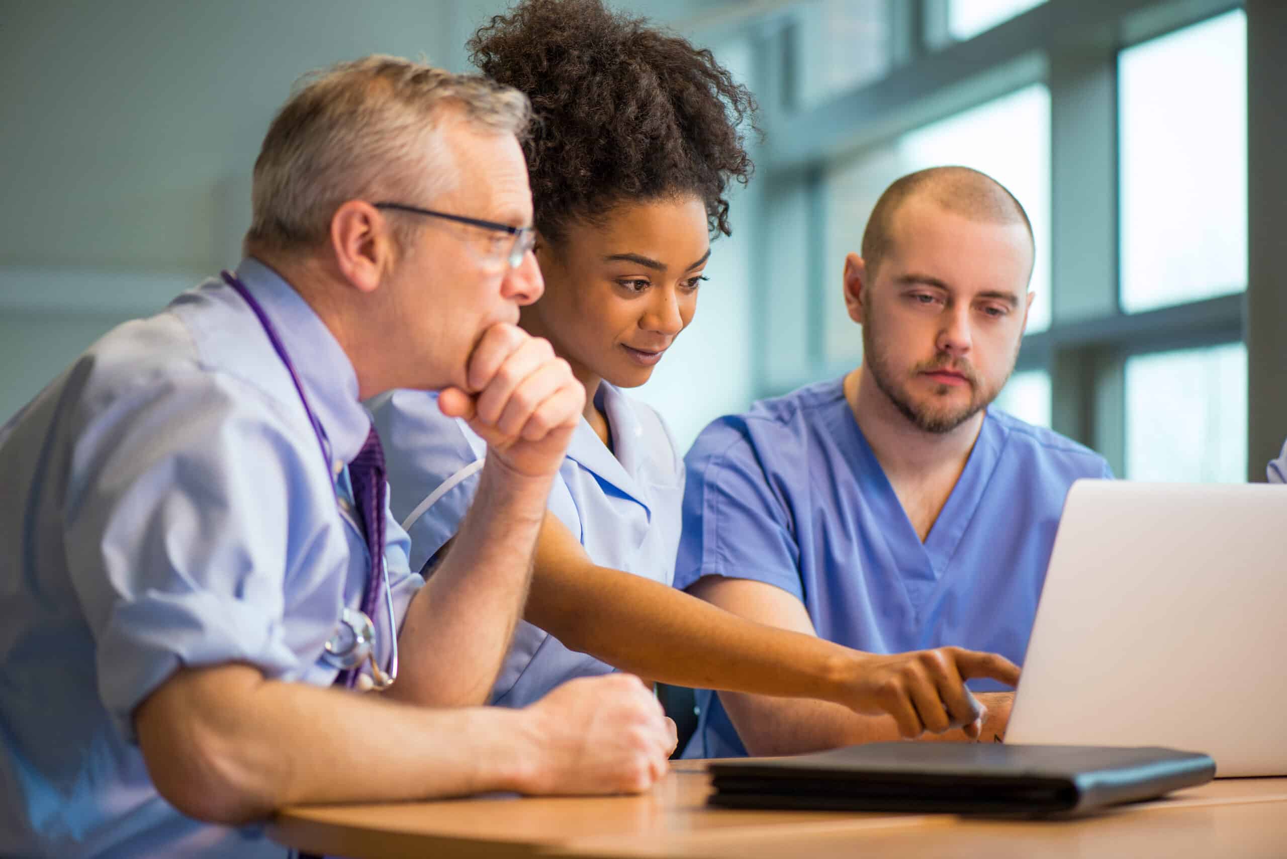 Healthcare workers reviewing unified patient data on a screen in a modern hospital setting.