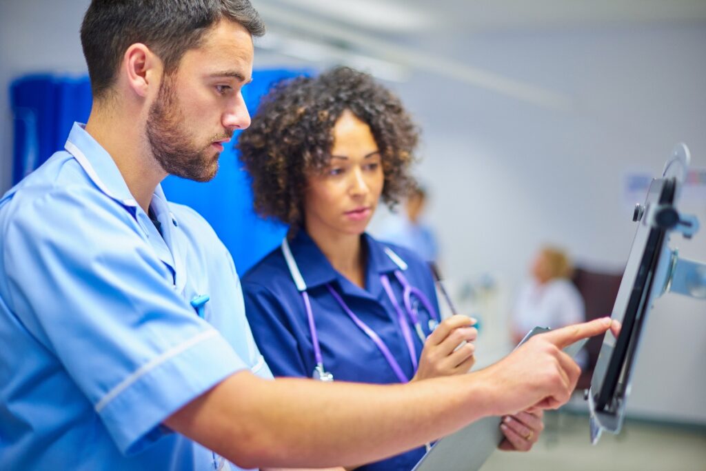 Two clinicians resolve patient identity details on a shared digital chart.