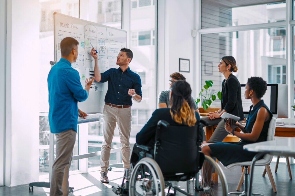 Colleagues gather around a whiteboard to plan their identity business initiative.
